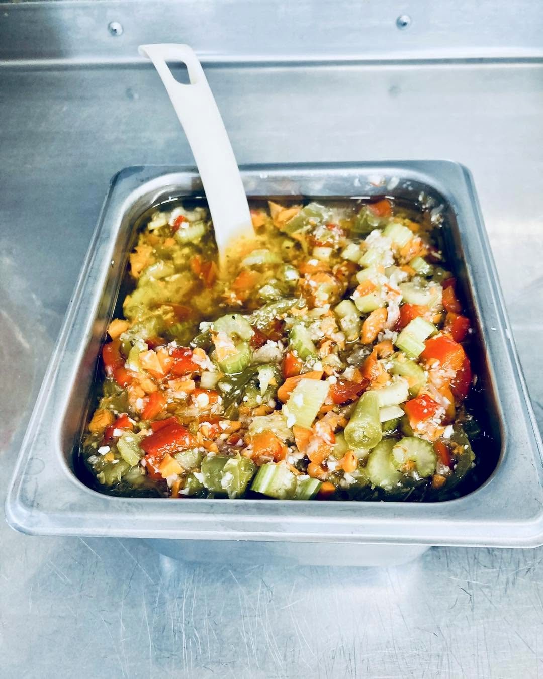 A full pan of giardiniera with a serving spoon