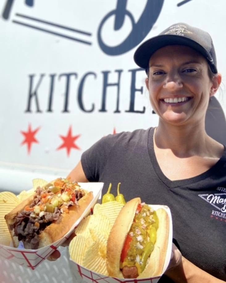 Big Mama — the Mama D's Kitchen food truck, with a beef sandwich and a Chicago dog in hand
